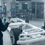 An engineer uses a tablet to analyze a vehicle chassis in a lab. The image illustrates modern mobility concepts.