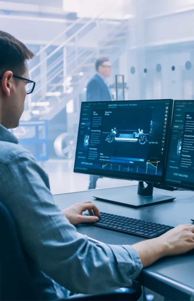 Ein Ingenieur nutzt eine Computersimulation, um ein Fahrzeugchassis im Detail zu analysieren. Dies ist Teil des Concept Consultings, bei dem technische Konzepte und Entwürfe bewertet und optimiert werden. Im Hintergrund ist ein weiterer Ingenieur zu sehen, der durch das Büro geht. Das Bild veranschaulicht den Beratungsprozess im Rahmen der Konzeptentwicklung. An engineer uses computer simulation to analyze a vehicle chassis in detail. This is part of concept consulting, where technical concepts and designs are evaluated and optimized. In the background, another engineer walks through the office. The image illustrates the consulting process within concept development.