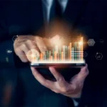 Eine Person in formeller Kleidung arbeitet auf einem Tablet mit leuchtenden Balkendiagrammen. Das Bild steht symbolisch für die Realisierungsplanung, bei der die Analyse von Daten eine Schlüsselrolle spielt, um erfolgreiche Strategien für die Umsetzung von Projekten zu entwickeln. A person in formal attire works on a tablet displaying glowing bar charts. The image symbolizes realization planning, where data analysis plays a key role in developing successful strategies for project execution.