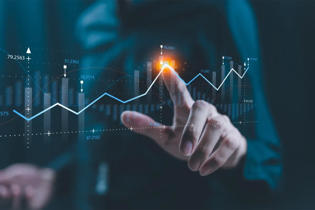 Eine Hand berührt eine digitale Grafik mit aufsteigenden Finanzdaten und Diagrammen. Die Darstellung zeigt den Prozess der Realisierungsplanung, bei dem Aspekte wie Finanzierung und GO2market-Plan für die Markteinführung berücksichtigt werden. A hand touches a digital chart displaying rising financial data and graphs. The representation reflects the implementation planning process, taking into account financing and the GO2market plan for product launch.