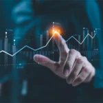 Eine Hand berührt eine digitale Grafik mit aufsteigenden Finanzdaten und Diagrammen. Die Darstellung zeigt den Prozess der Realisierungsplanung, bei dem Aspekte wie Finanzierung und GO2market-Plan für die Markteinführung berücksichtigt werden. A hand touches a digital chart displaying rising financial data and graphs. The representation reflects the implementation planning process, taking into account financing and the GO2market plan for product launch.