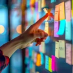 Eine Hand zeigt auf eine Glaswand, die mit bunten Haftnotizen bedeckt ist. Dieses Bild symbolisiert das Consulting in der Konzeptphase, bei dem Ideen und Strategien strukturiert und organisiert werden. A hand points to a glass wall covered with colorful sticky notes. This image symbolizes consulting in the concept phase, where ideas and strategies are structured and organized.
